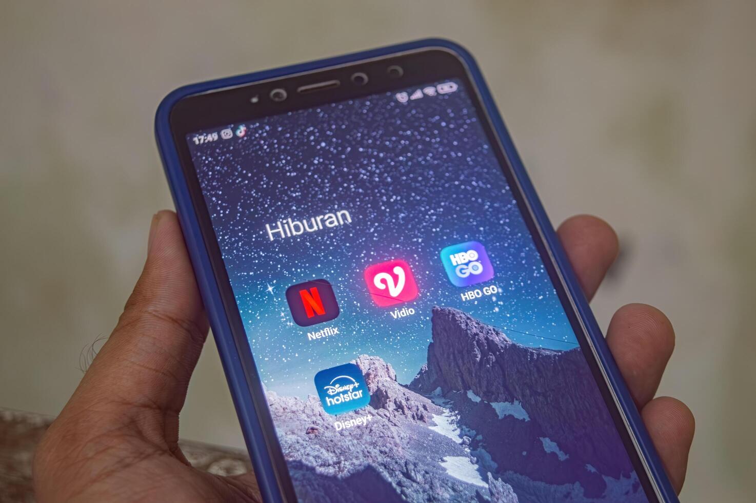 hand holding a Xiaomi Android smartphone with a screen displaying a collection of film player or online cinema applications, Indonesia, 12 May 2024. photo