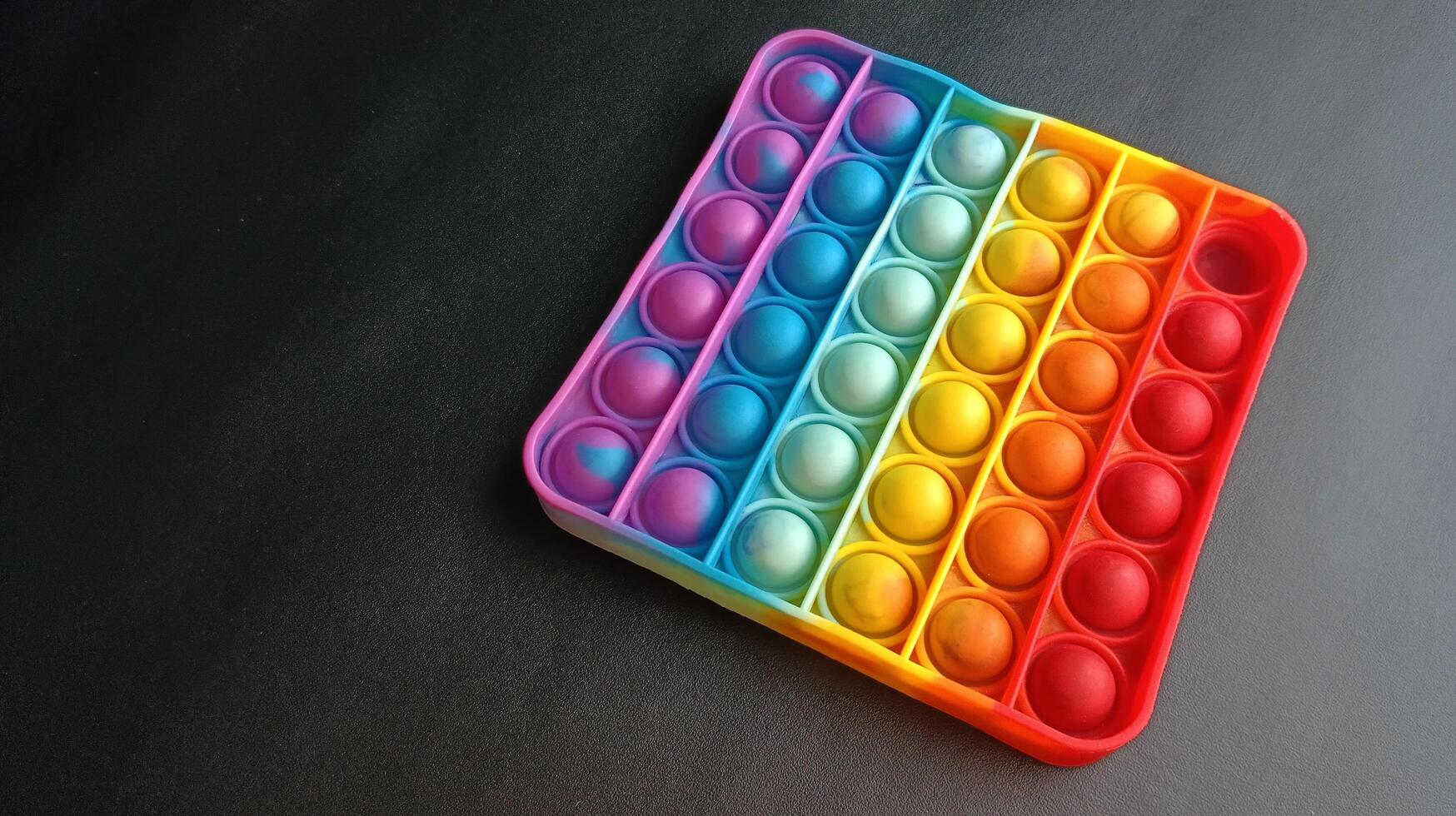 poppit toy on black background, close-up. Colorful poppit it game photo