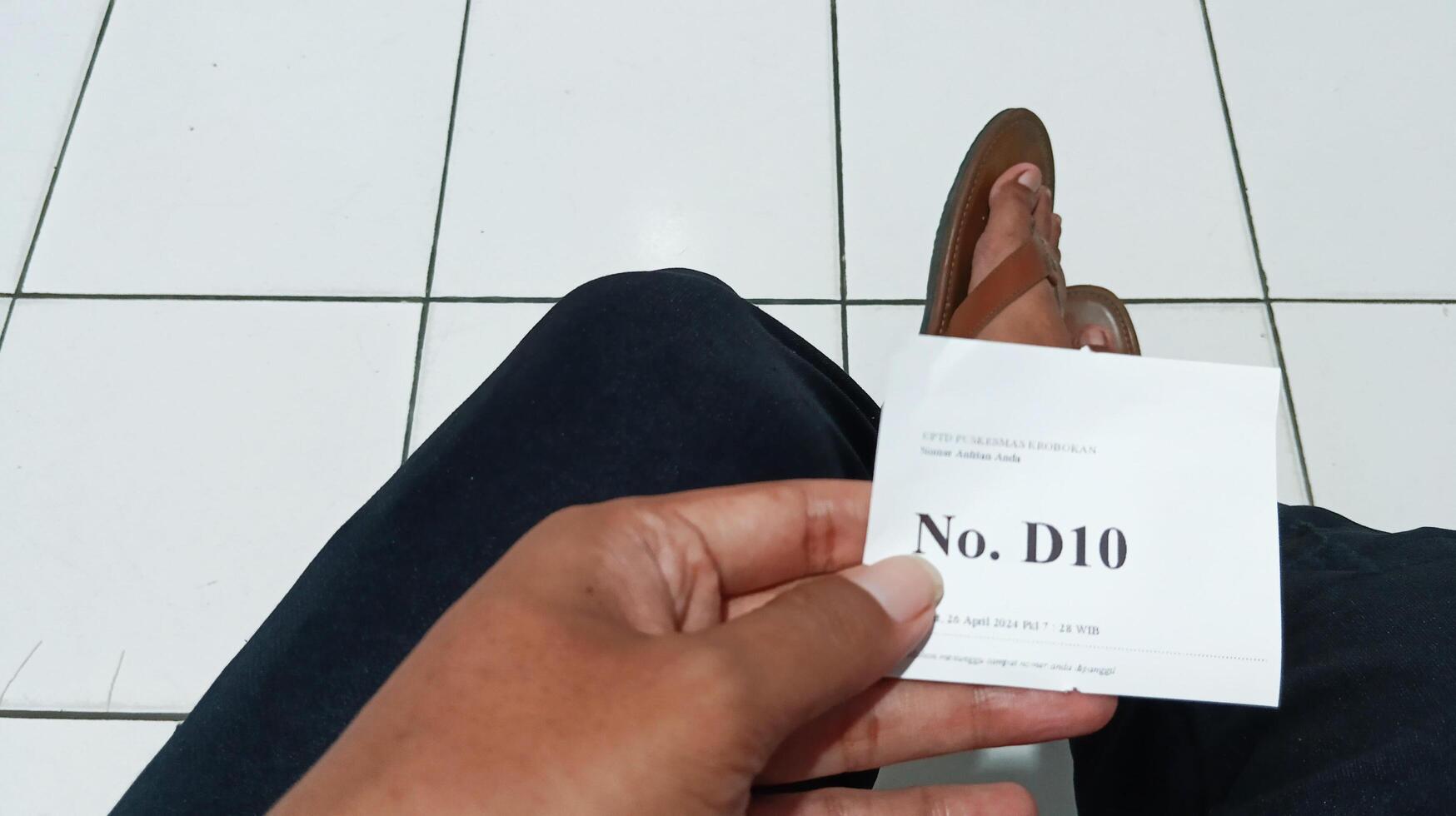 Someone's hand holding the queue number to see a doctor photo