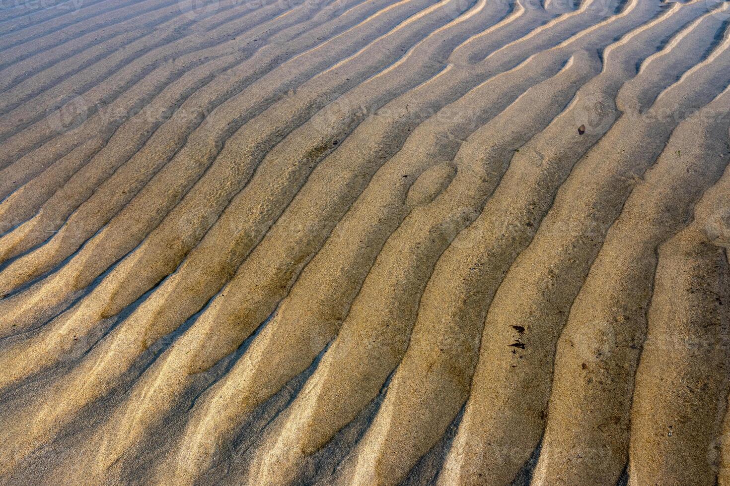 water furrows on the shore of a beach during low tide at sunset photo