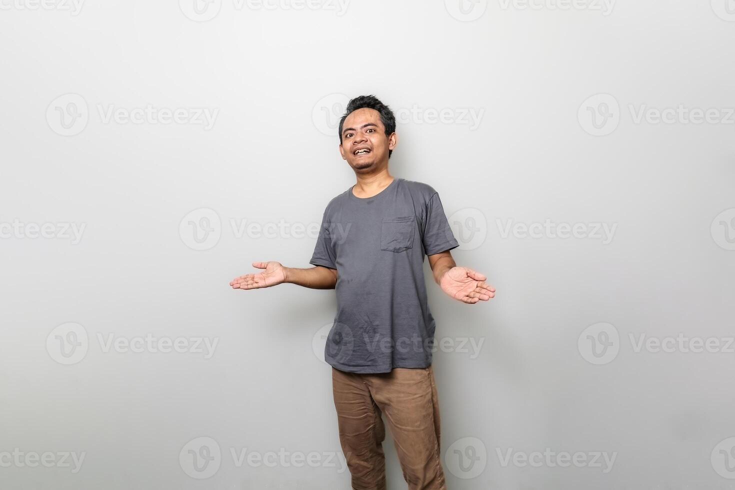 Young Asian asian man is confused when standing over white wall. Looking at camera. photo