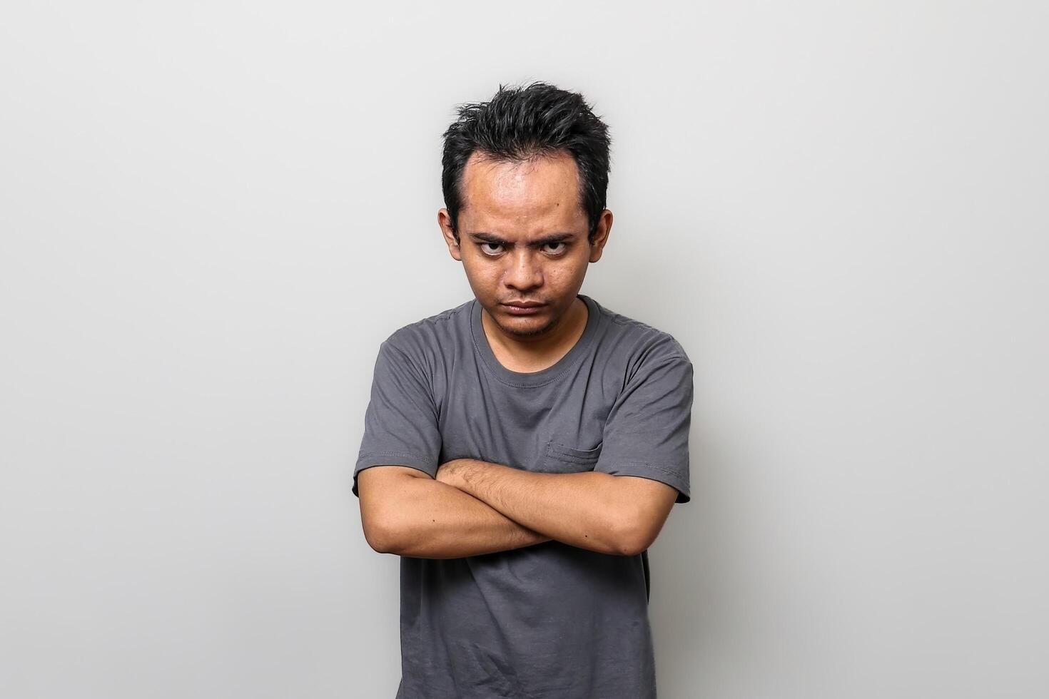an Asian man in gray was very angry with his arms crossed with a serious face photo