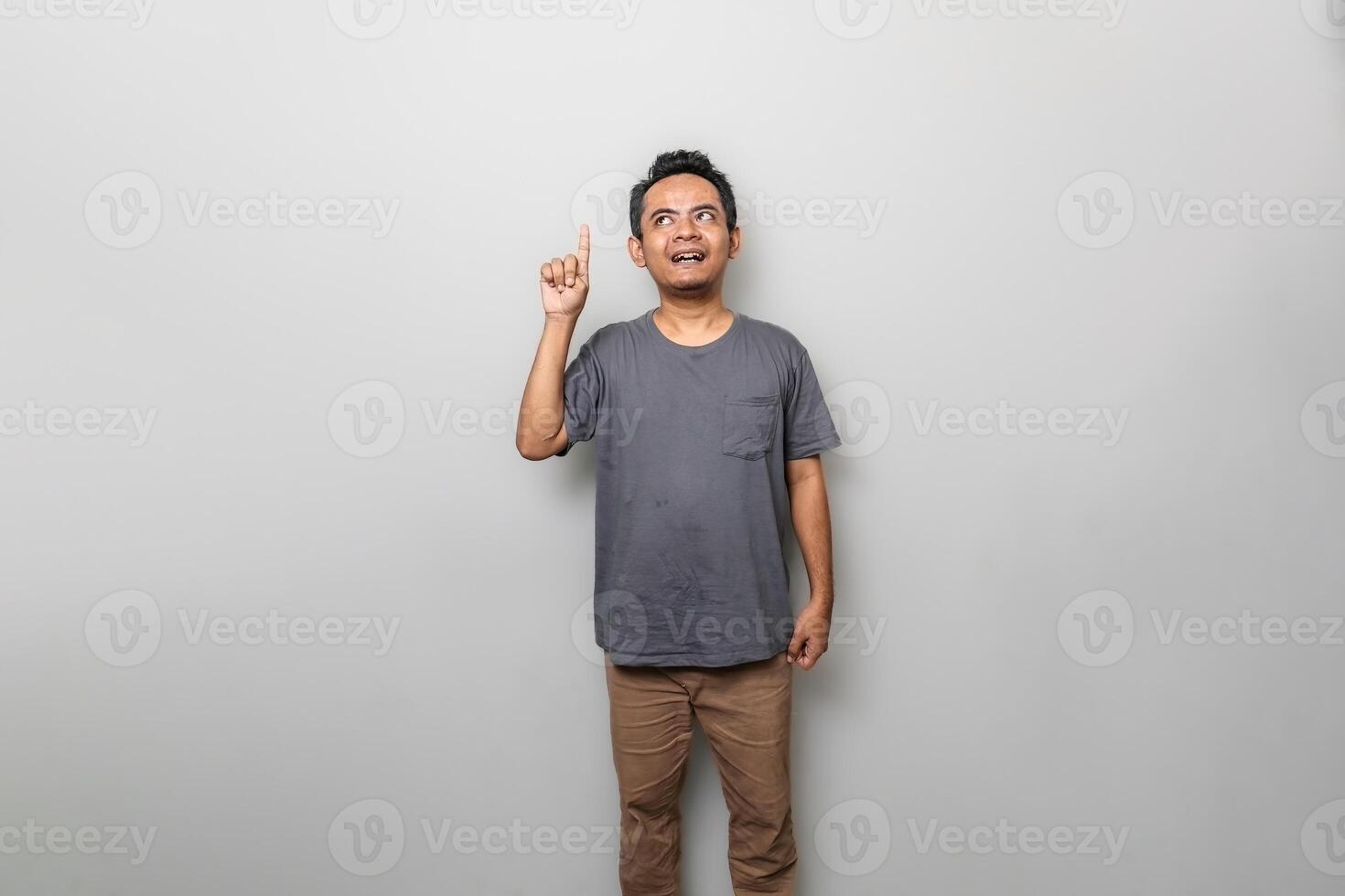 an asian man in gray is getting an idea while looking and pointing upwards isolated on white background photo