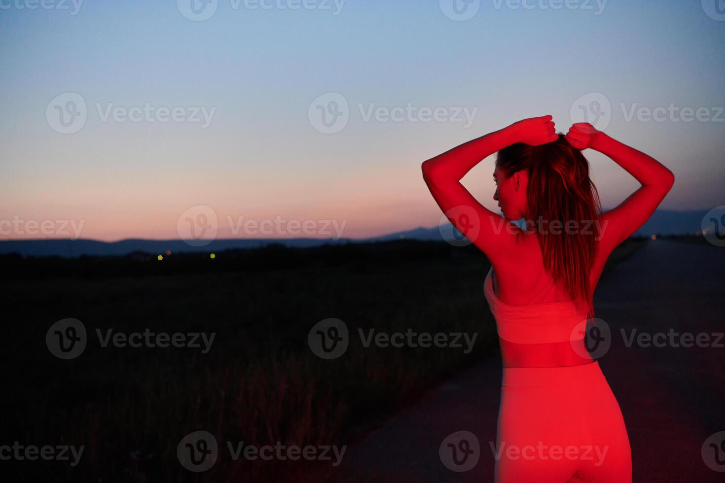 Athlete Strikes a Pose in Red-Lit Nighttime Glow photo
