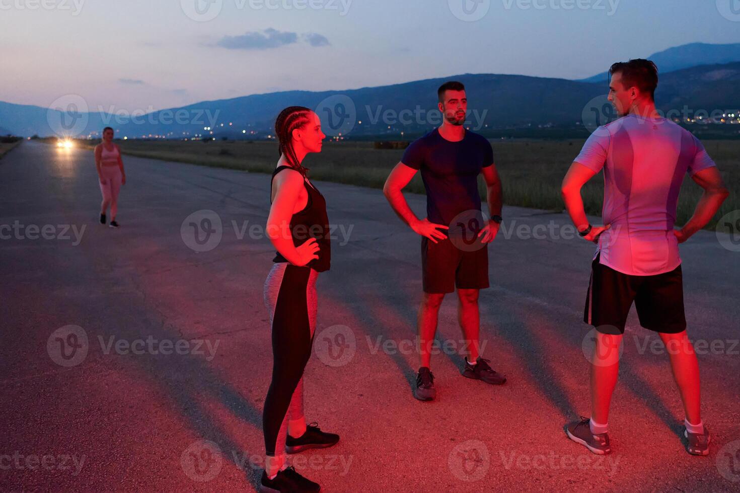 Diverse Athletes Unwind. Post-Marathon Rest Under Red Nighttime Glow. photo
