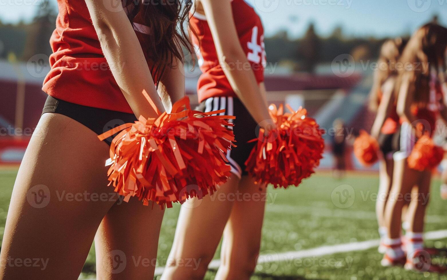 Photo of beautiful and young girls cheerleaders with colored pompoms in their hands for active support of sports team
