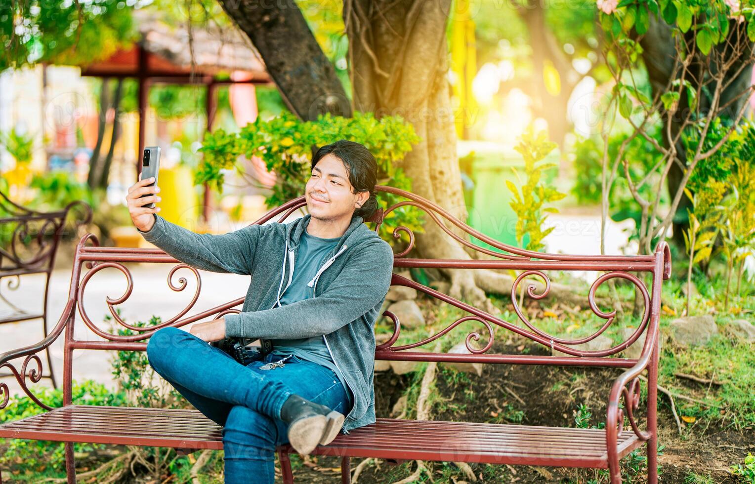 Smiling man sitting on a bench taking a selfie in Nagarote Park. Relaxed guy taking a selfie sitting on a bench in Nagarote Park photo