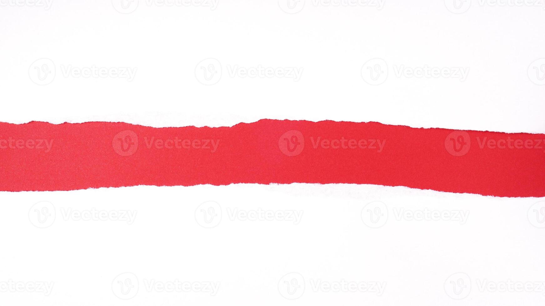 torn white sheet of paper with rough edges revealing red background with copy space photo