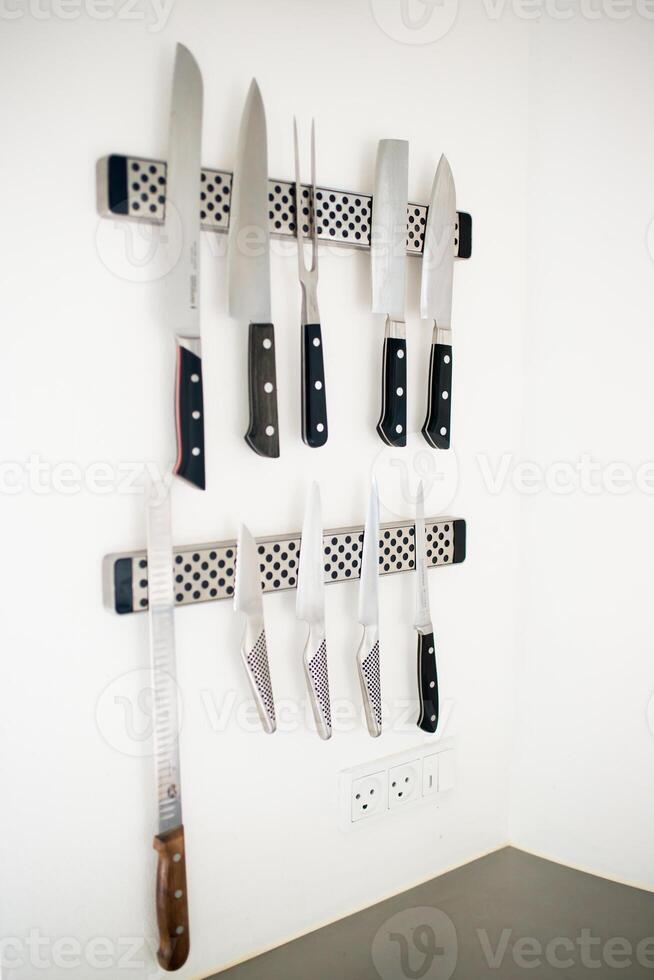 Set of professional knives on a white wall photo