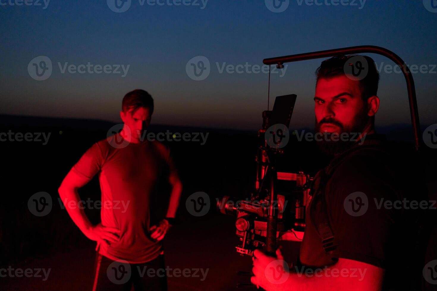 Nighttime Capture. Professional Videographer Films Athletes Running in Red-Lit Darkness photo