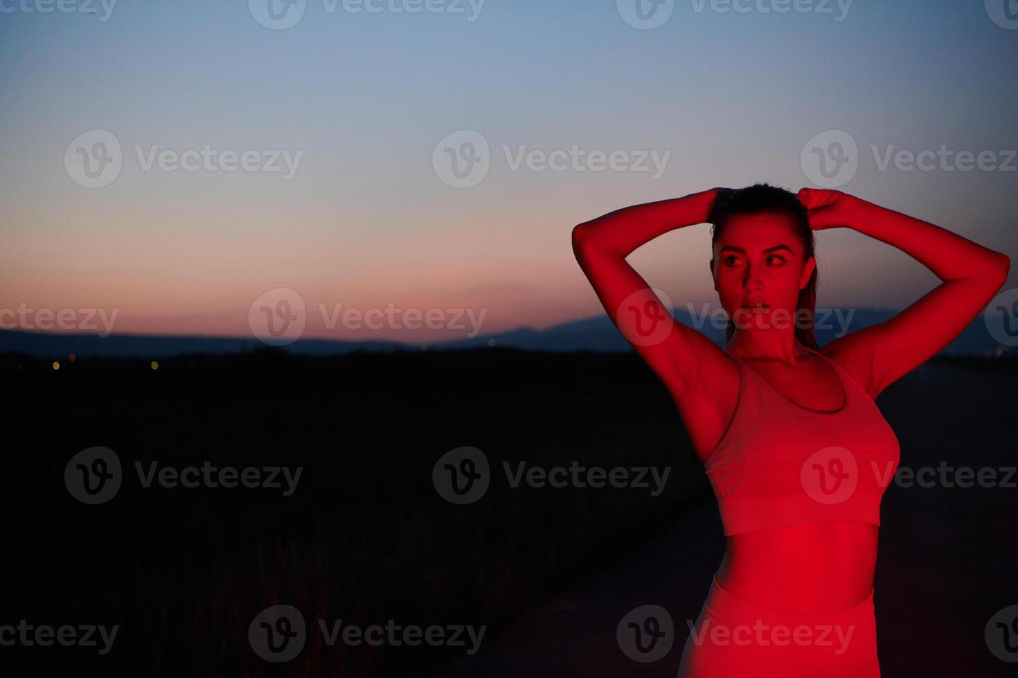 Athlete Strikes a Pose in Red-Lit Nighttime Glow photo