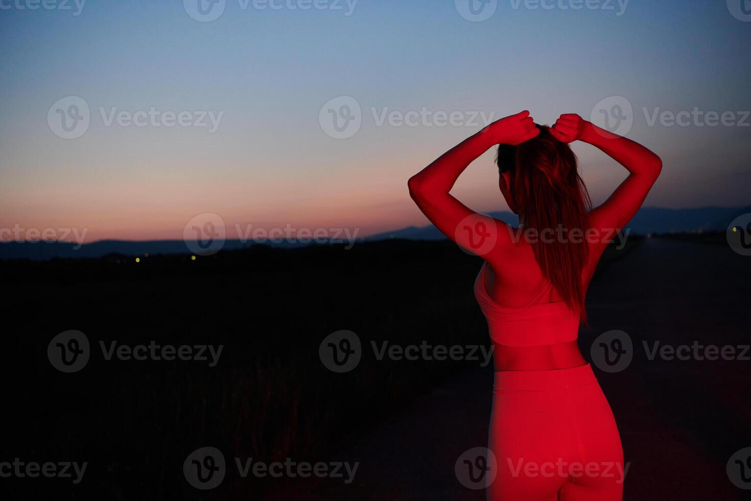 Athlete Strikes a Pose in Red-Lit Nighttime Glow photo