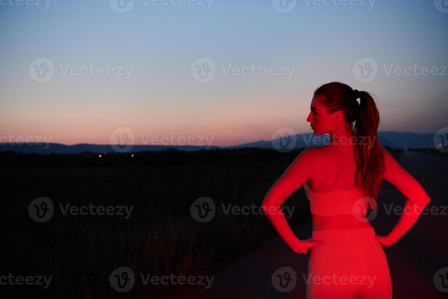 Athlete Strikes a Pose in Red-Lit Nighttime Glow photo