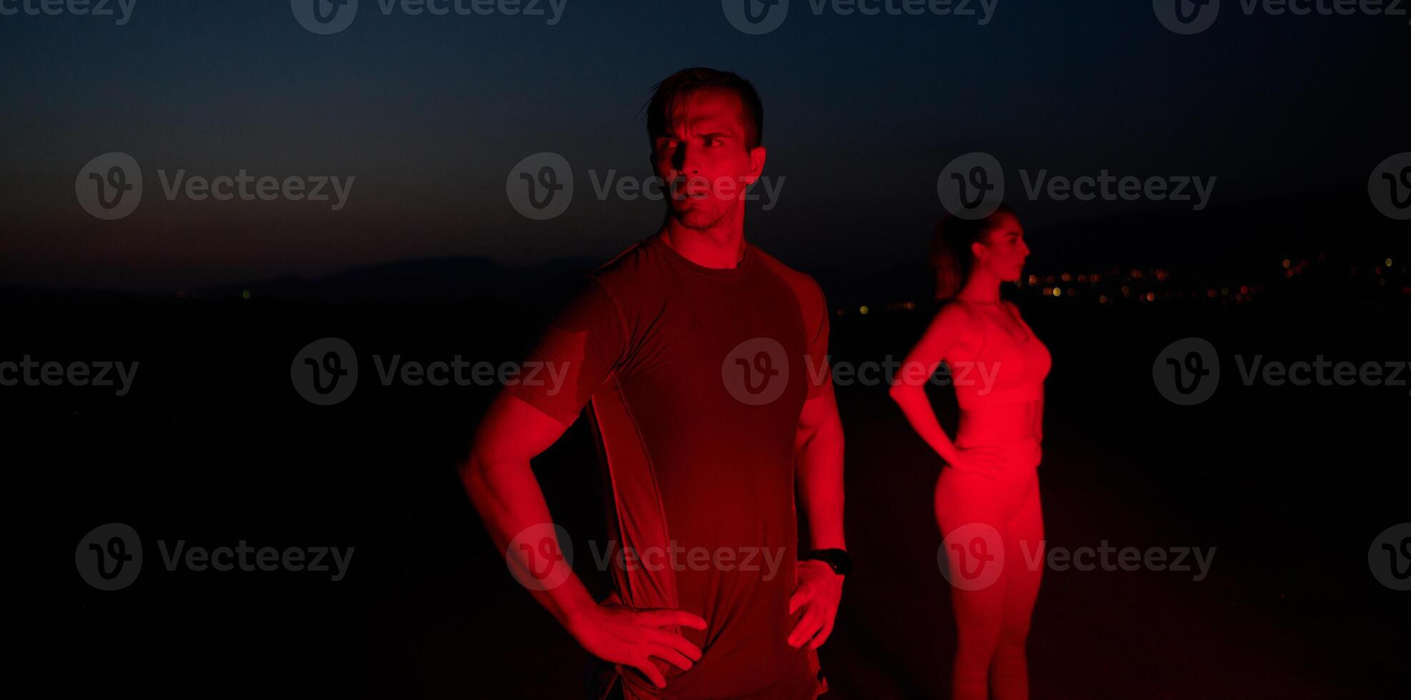 Athlete Strikes a Pose Under Red Nighttime Glow After Intense Daylong Marathon. photo