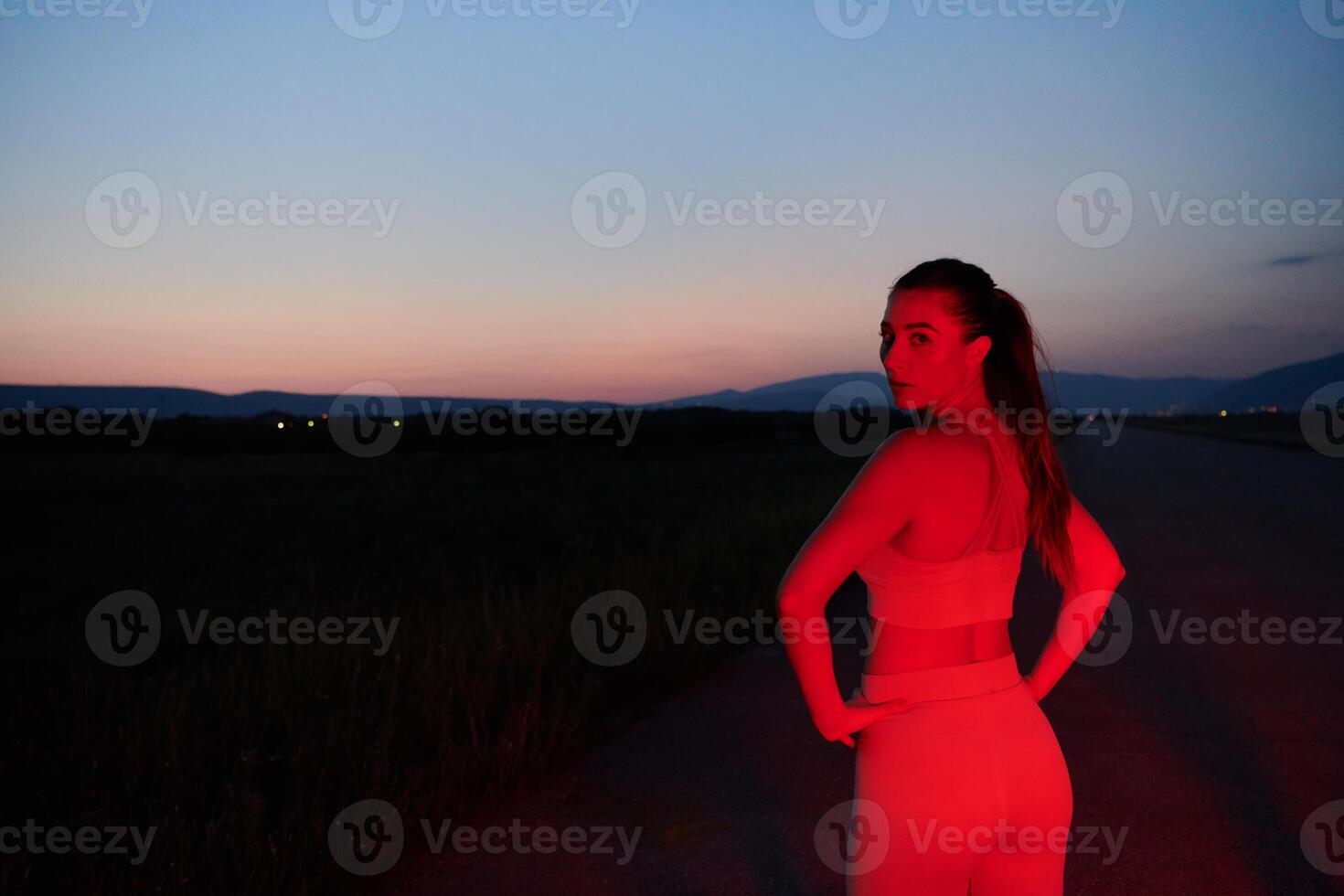 Athlete Strikes a Pose in Red-Lit Nighttime Glow photo
