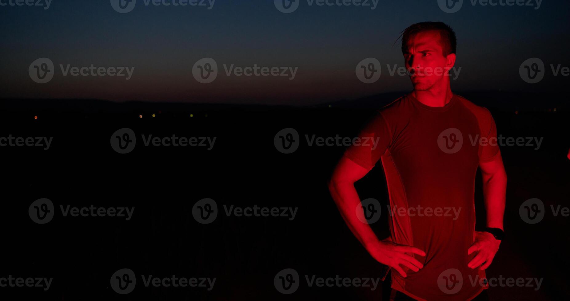 Athlete Strikes a Pose Under Red Nighttime Glow After Intense Daylong Marathon. photo
