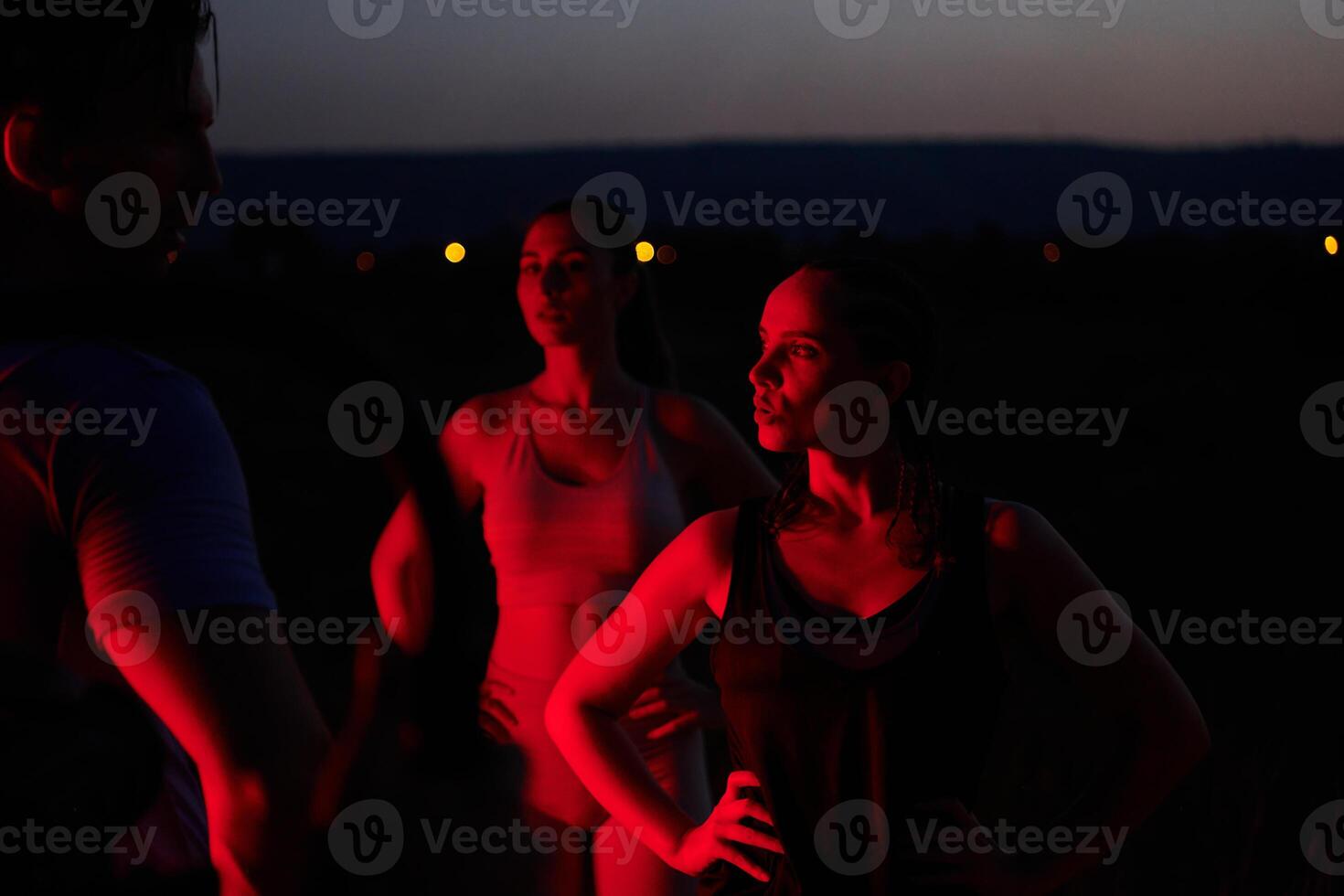 Diverse Athletes Unwind. Post-Marathon Rest Under Red Nighttime Glow. photo