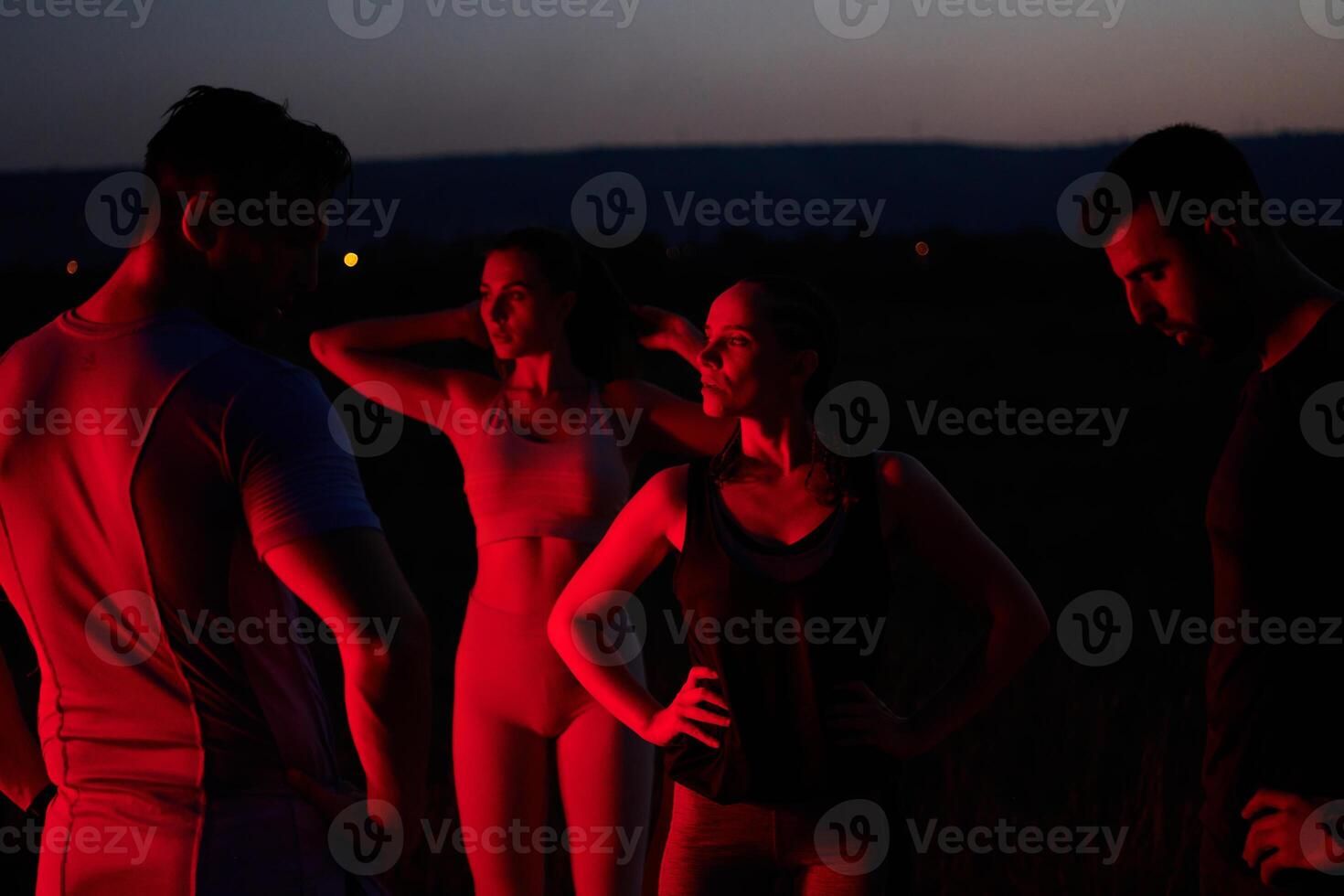Diverse Athletes Unwind. Post-Marathon Rest Under Red Nighttime Glow. photo