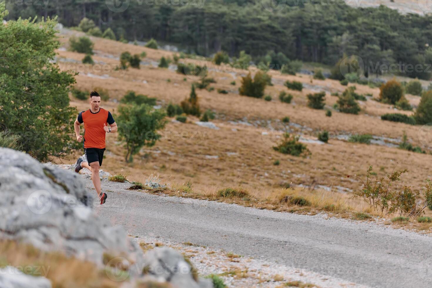 Determined Athlete Running Through Rugged Mountain Terrain at Sunrise. photo