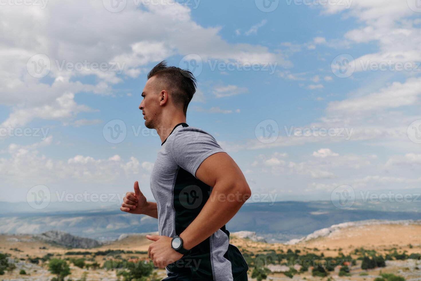 Determined Athlete Running Through Rugged Mountain Terrain at Sunrise. photo