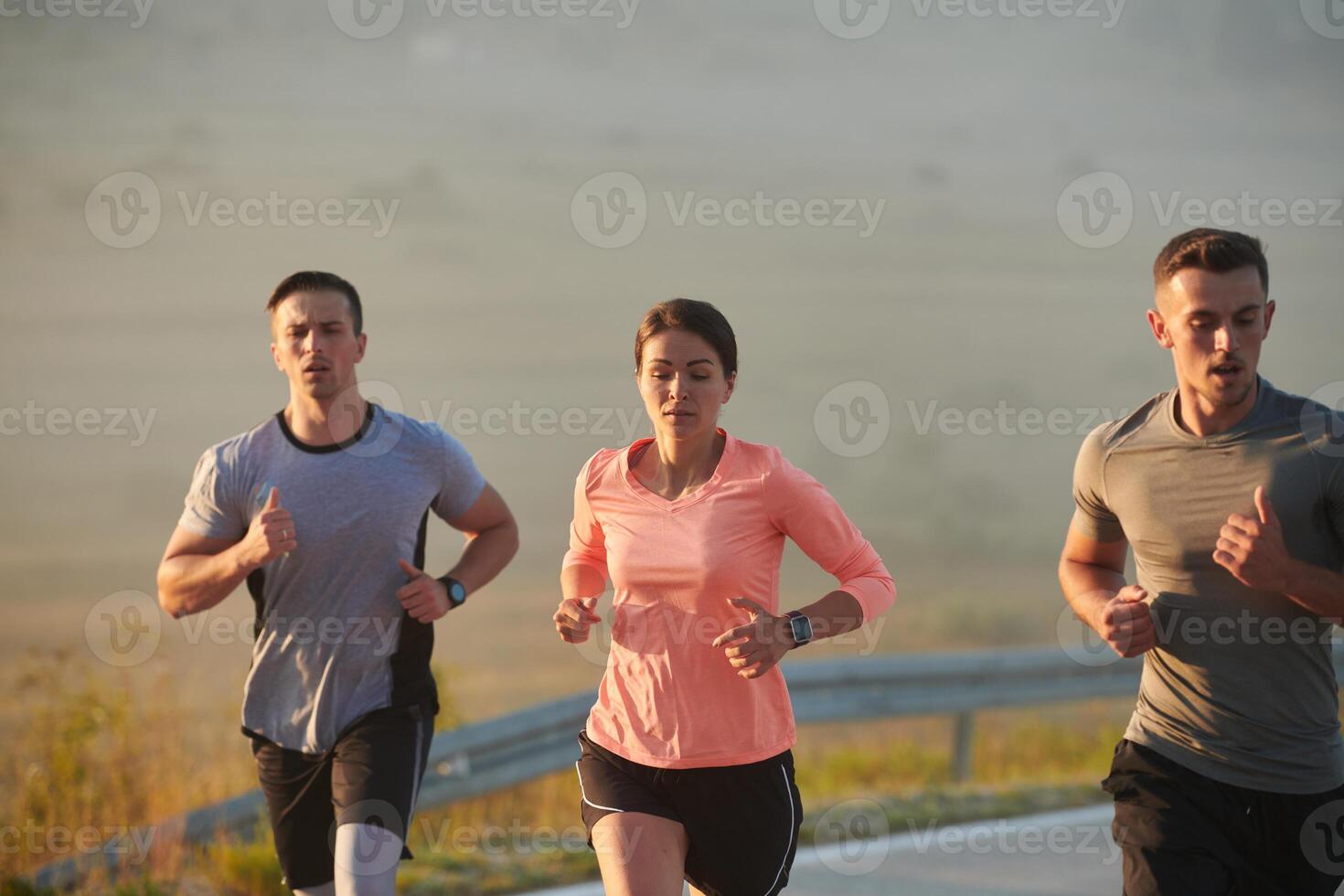 A group of friends, athletes, and joggers embrace the early morning hours as they run through the misty dawn, energized by the rising sun and surrounded by the tranquil beauty of nature photo