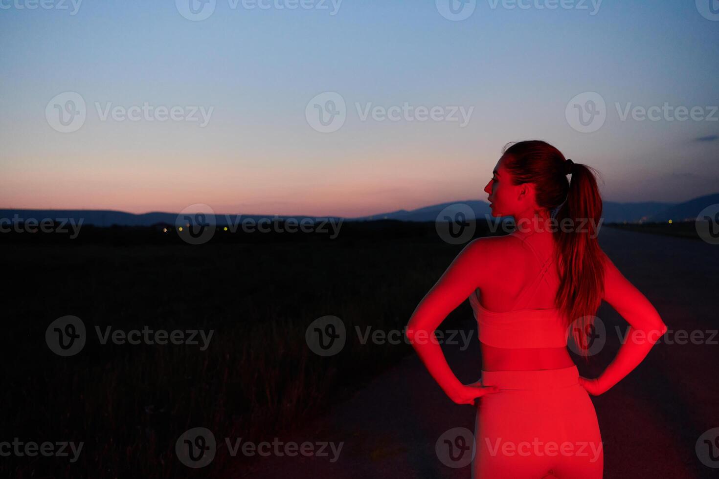 Athlete Strikes a Pose in Red-Lit Nighttime Glow photo
