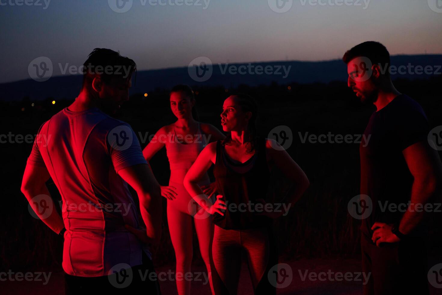 Diverse Athletes Unwind. Post-Marathon Rest Under Red Nighttime Glow. photo