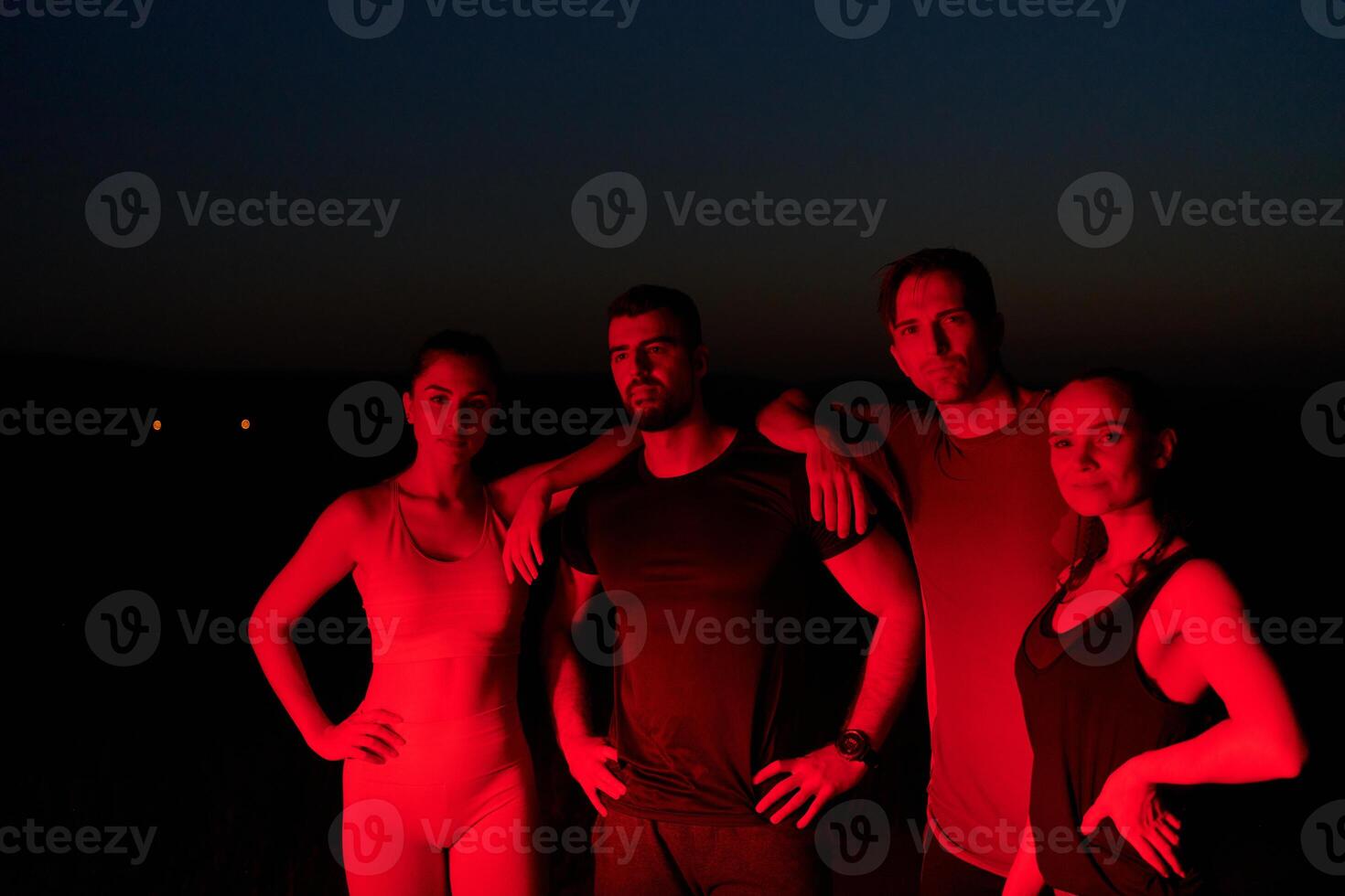 Diverse Athletes Unwind. Post-Marathon Rest Under Red Nighttime Glow. photo