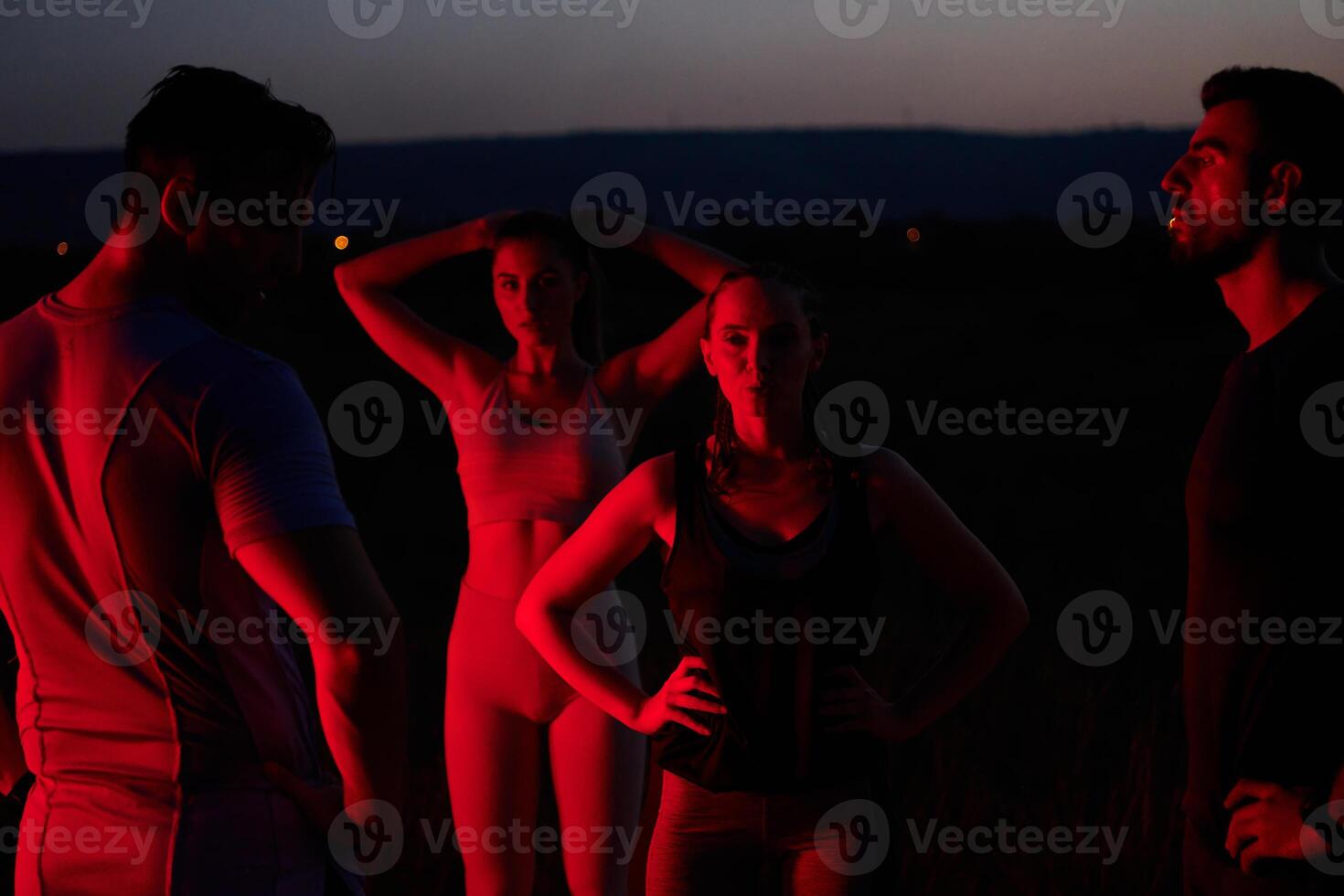 Diverse Athletes Unwind. Post-Marathon Rest Under Red Nighttime Glow. photo