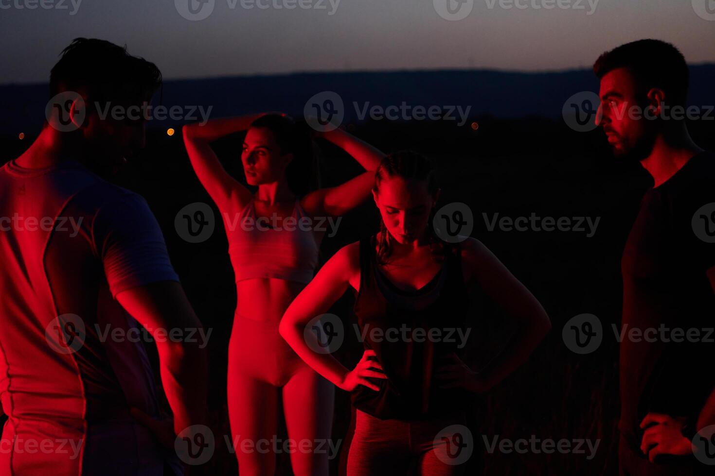 Diverse Athletes Unwind. Post-Marathon Rest Under Red Nighttime Glow. photo