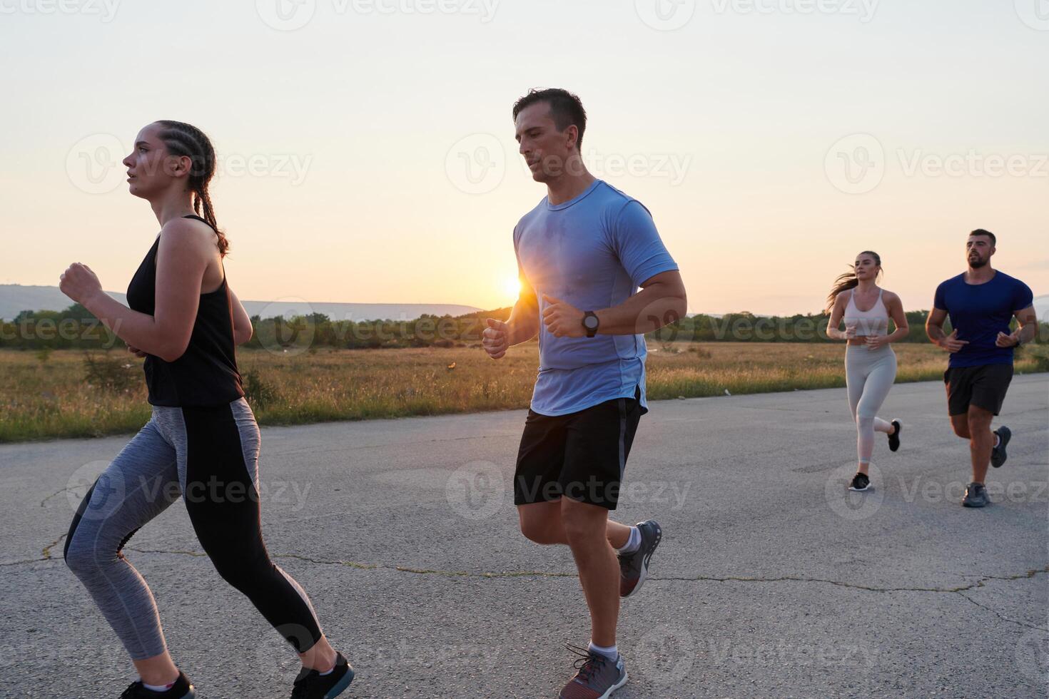 A diverse group of runners trains together at sunset. photo