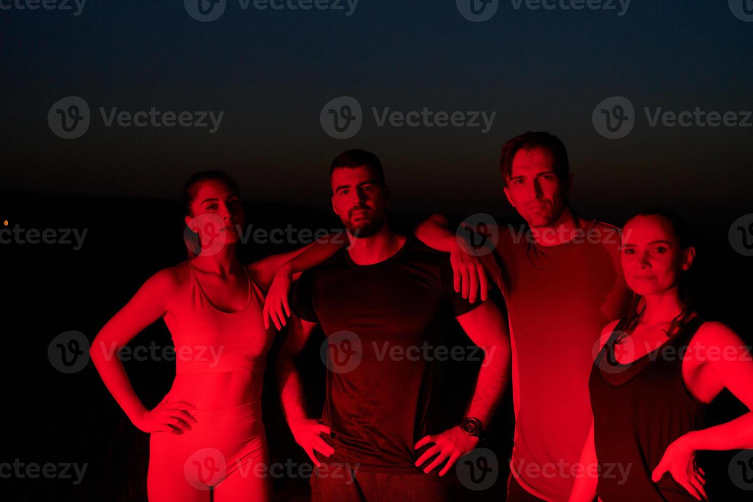 Diverse Athletes Unwind. Post-Marathon Rest Under Red Nighttime Glow. photo
