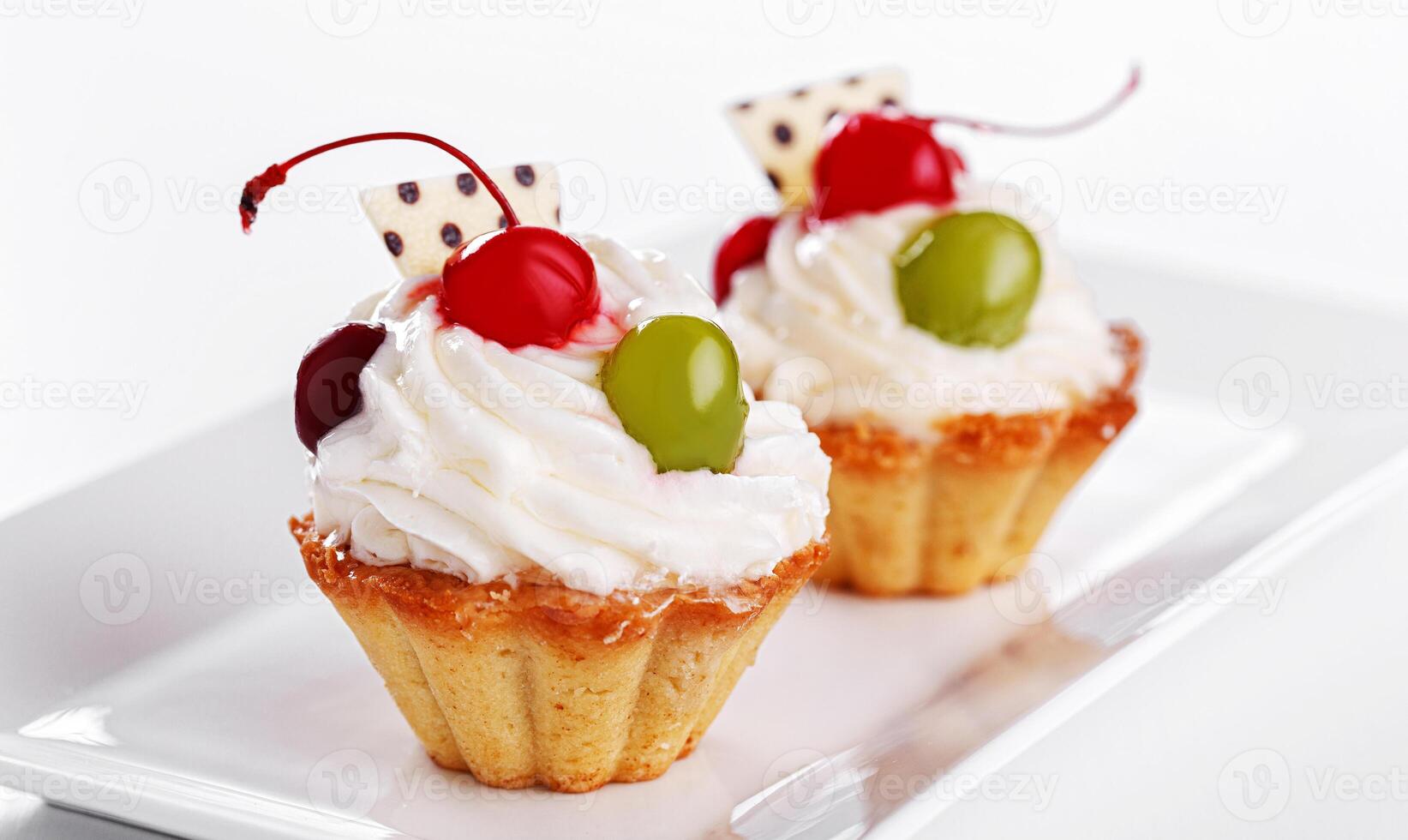 Beautiful cream cakes with cherries and grapes on a plate on a white background photo