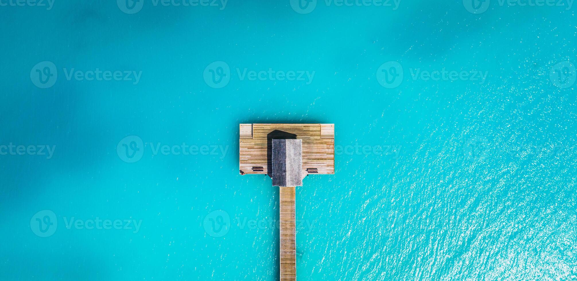 Aerial view of Maldives island, luxury water villas resort and wooden pier. Beautiful sky and ocean lagoon beach background. Summer vacation holiday and travel concept. Paradise aerial landscape pano photo