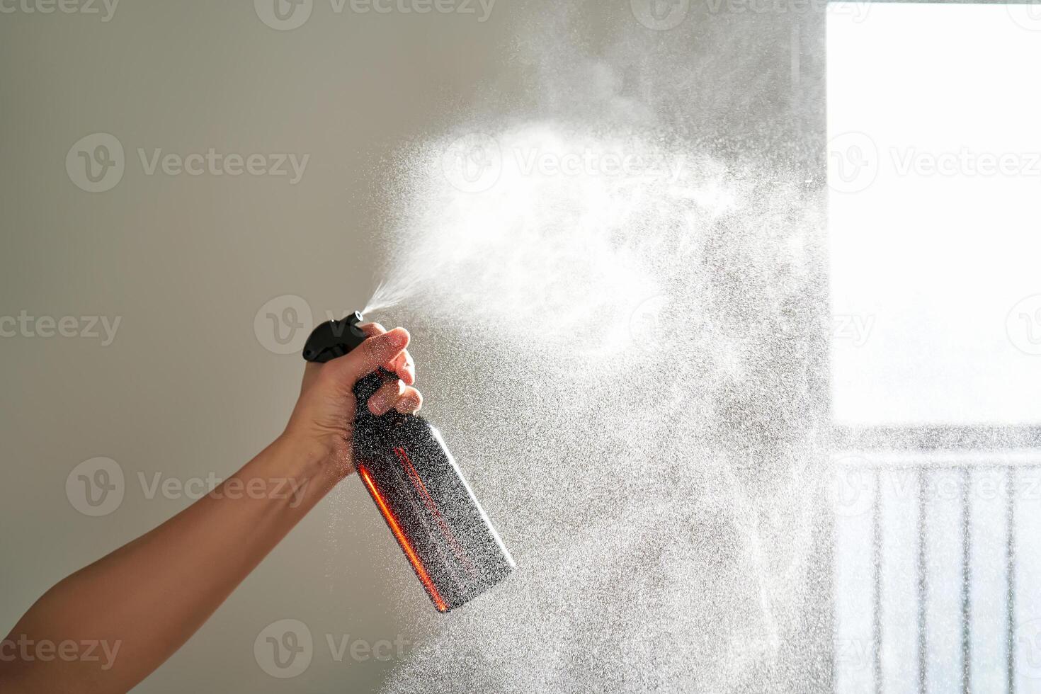 A woman's hand sprays an air freshener in a room. photo