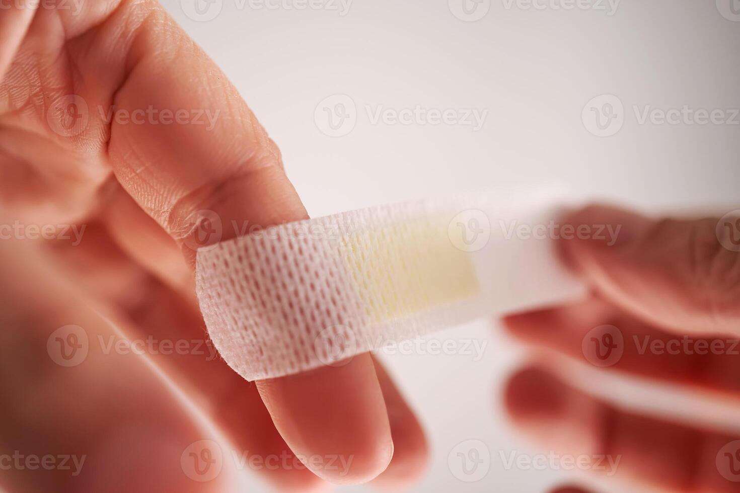 Applying an adhesive plaster to a finger. Close-up. photo