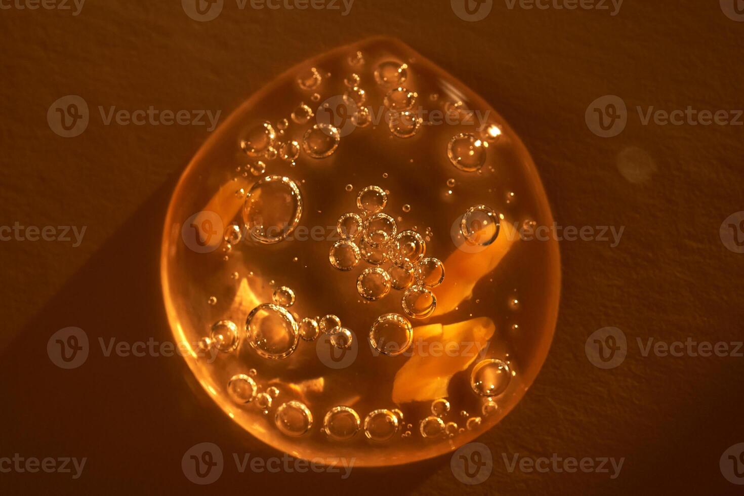 Drop of serum shimmering in the sun on a beige background. photo