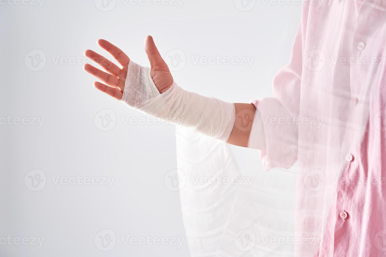 A woman in a pink shirt holds a bandage and puts a bandage on her arm. photo