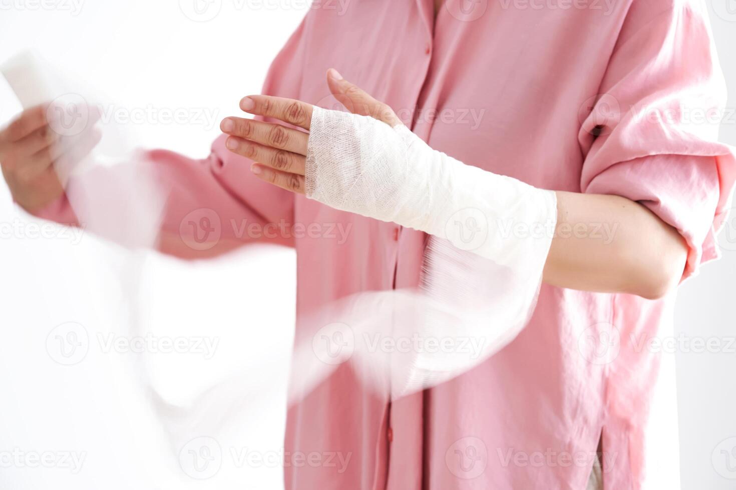 A woman in a pink shirt holds a bandage and puts a bandage on her arm. photo
