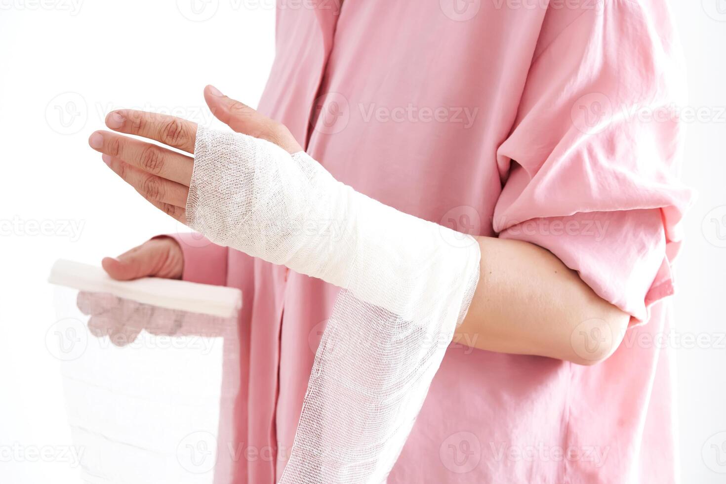 A woman in a pink shirt holds a bandage and puts a bandage on her arm. photo