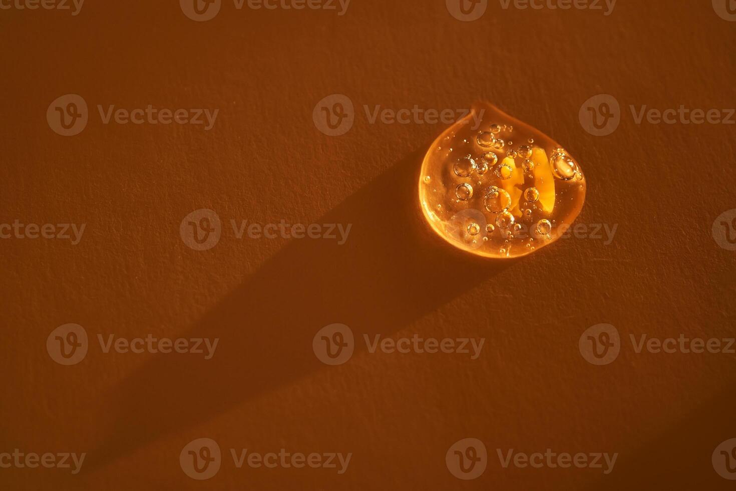 Drop of serum shimmering in the sun on a beige background. photo