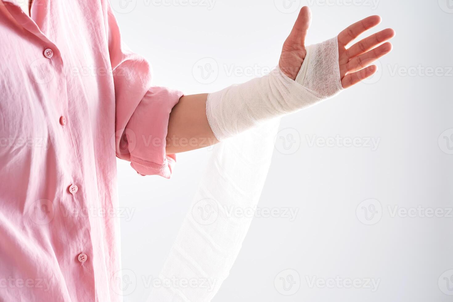 A woman in a pink shirt holds a bandage and puts a bandage on her arm. photo