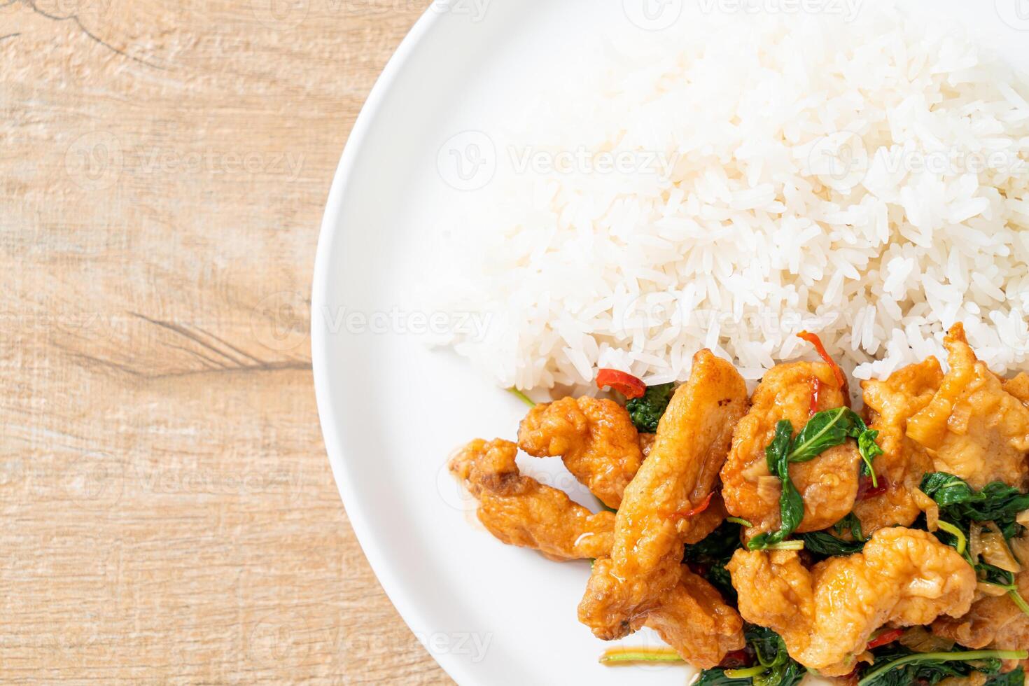 stir-fried fried fish with basil and chili in thai style topped on rice photo