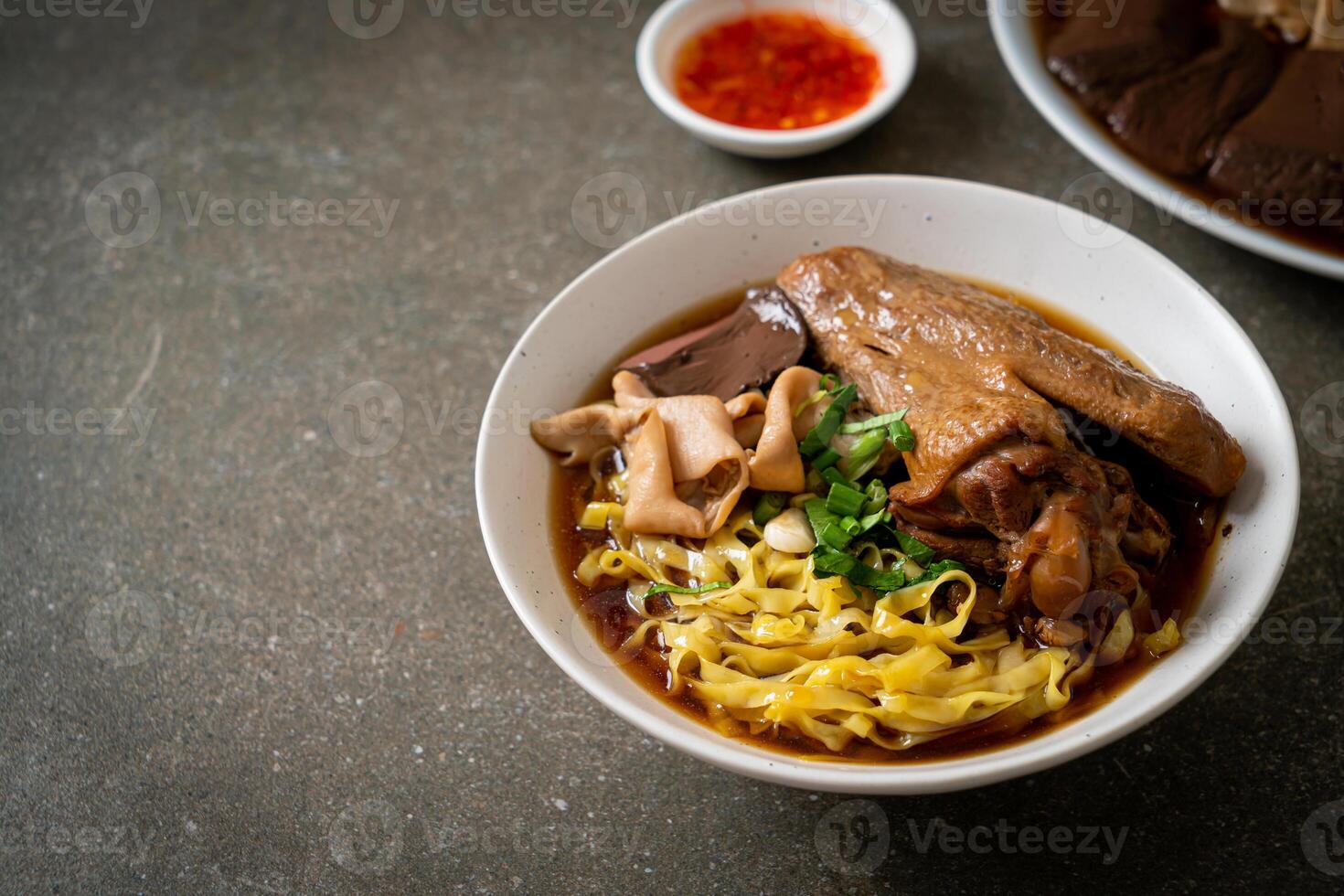 egg noodles with stewed and braised duck in brown soup photo