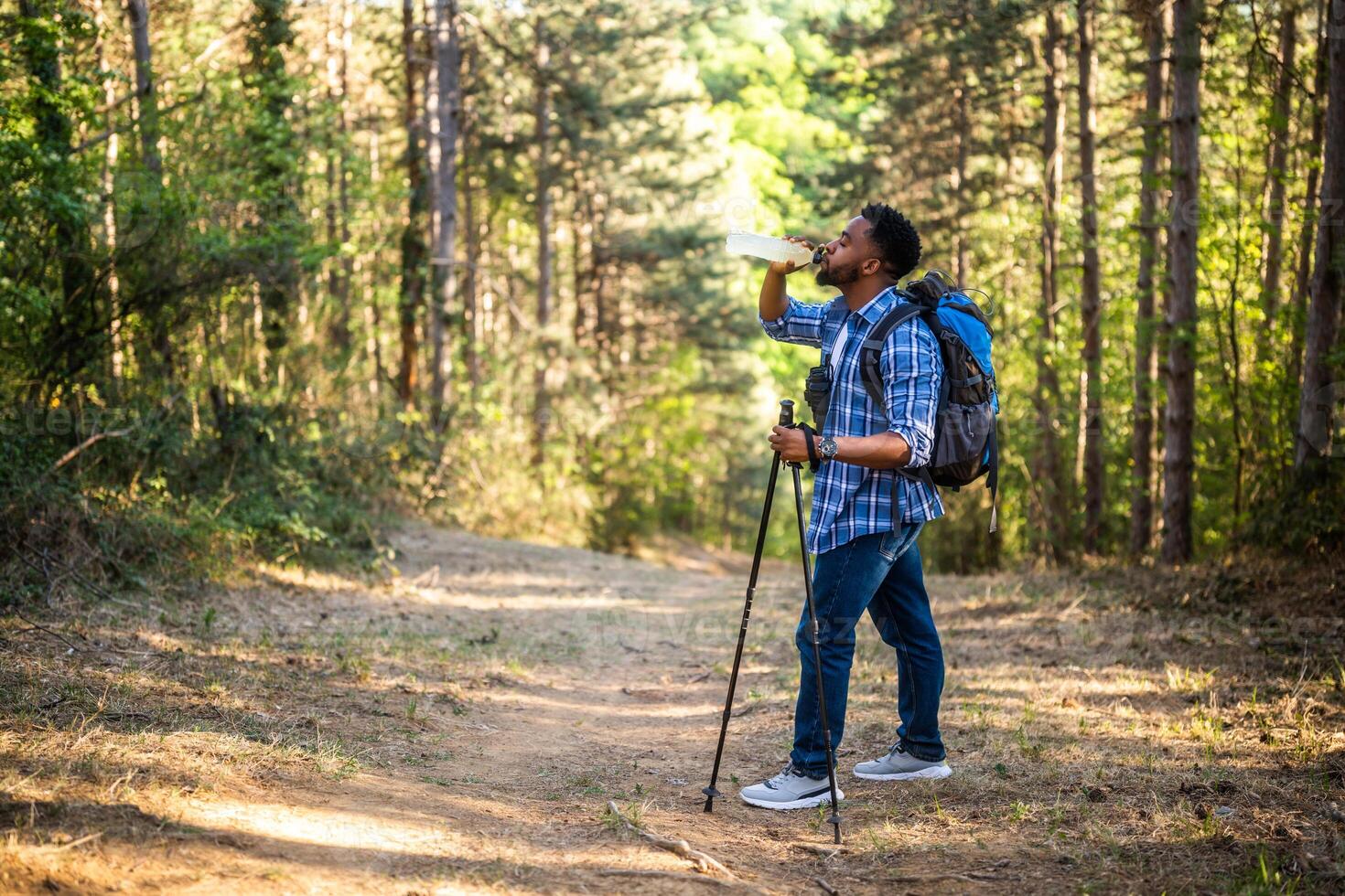 Young man enjoys hiking and drinking energy drink. photo
