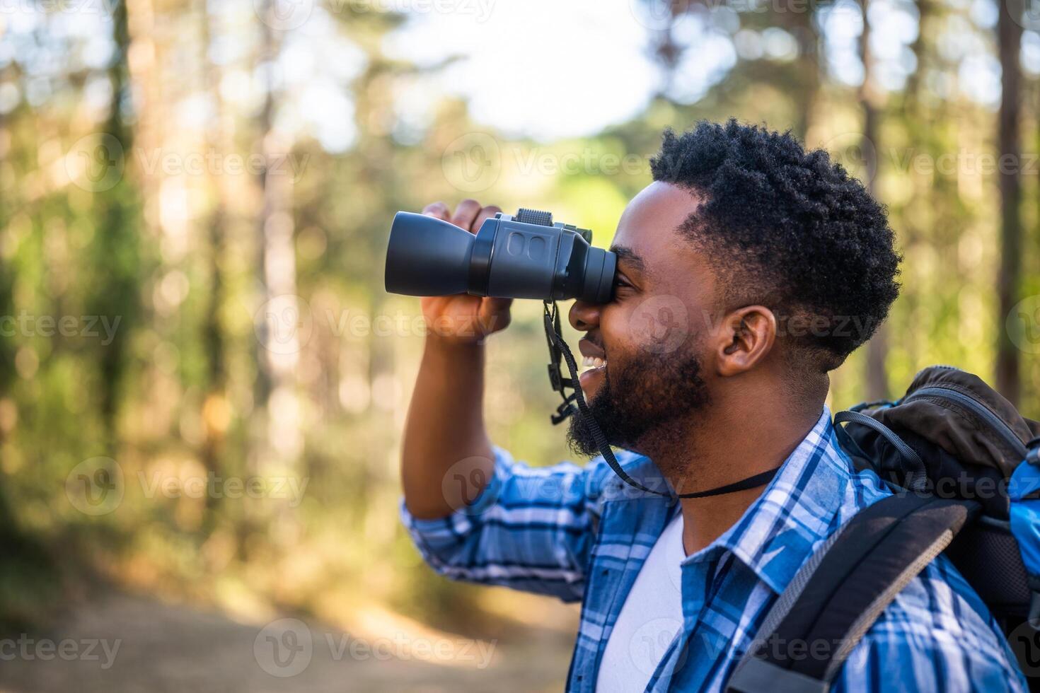 Young man enjoys using binoculars and hiking in nature. photo