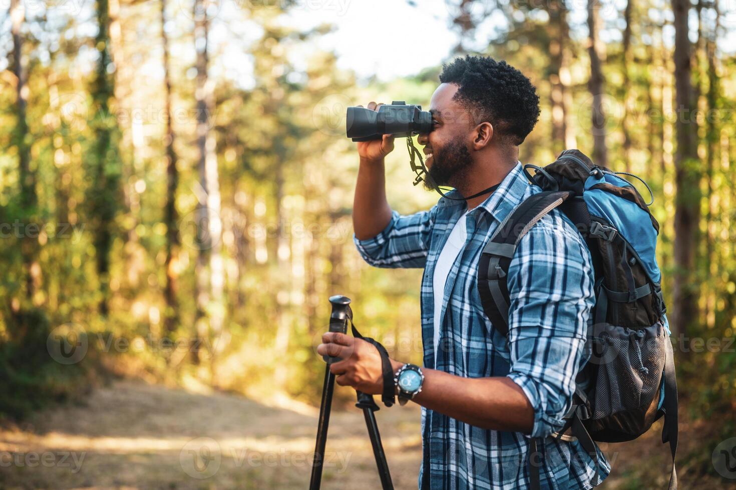 Young man enjoys using binoculars and hiking in nature photo