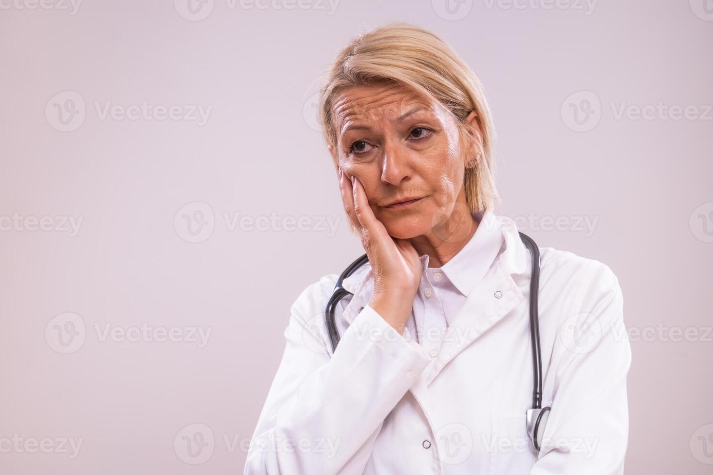 Portrait of tired mature female doctor on gray background photo