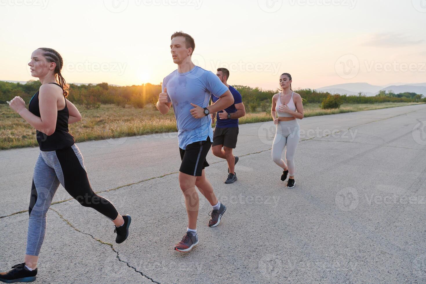 A diverse group of runners trains together at sunset. photo