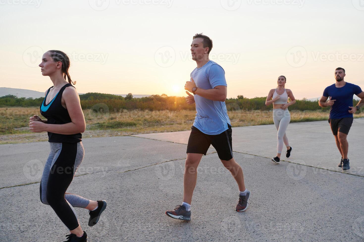 A diverse group of runners trains together at sunset. photo